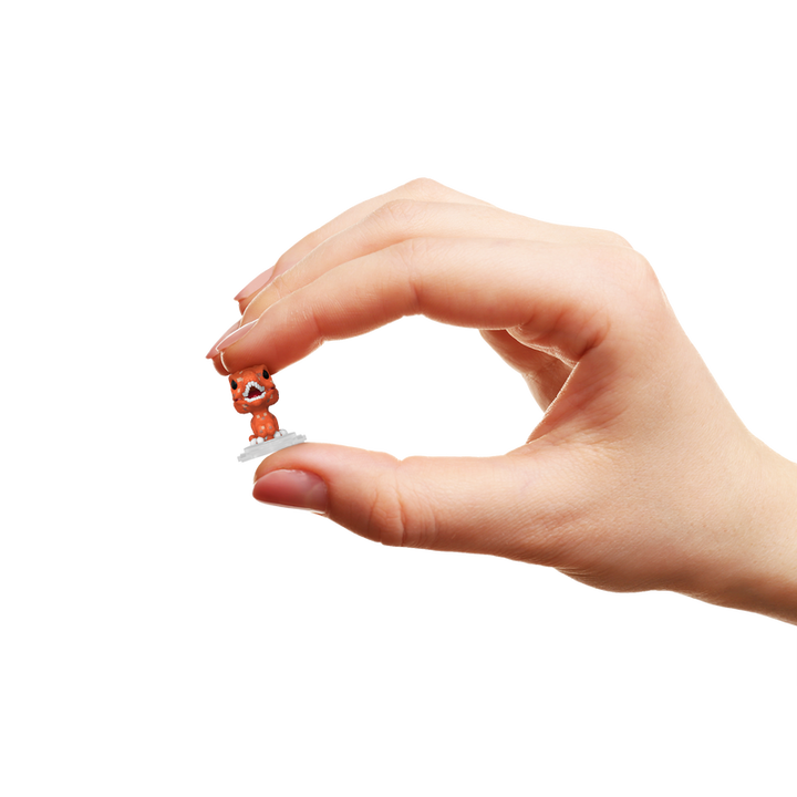 Hand holding a small orange figurine with a white background