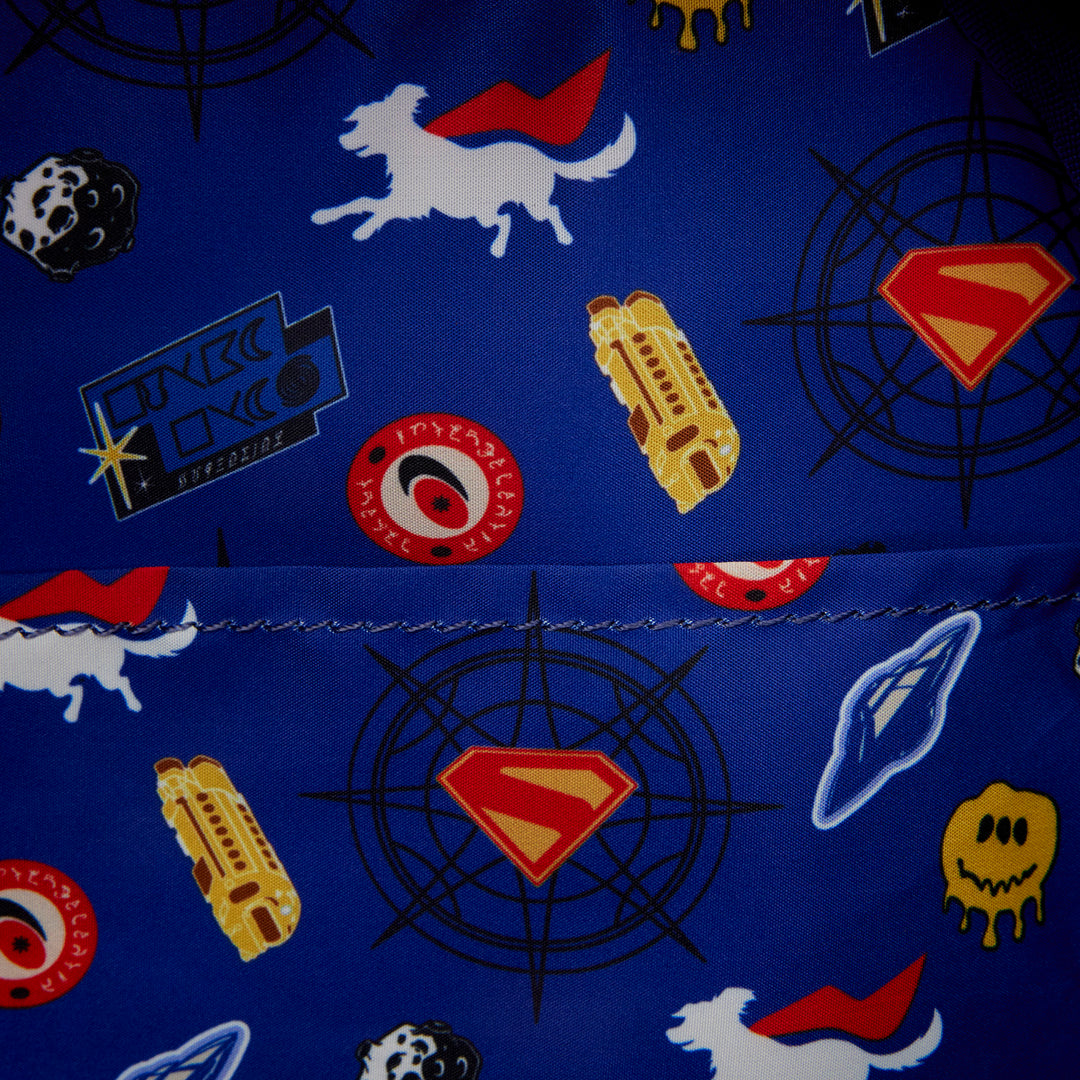Close-up of a blue fabric with superhero-themed patterns including Superman logo, rocket, and alien.