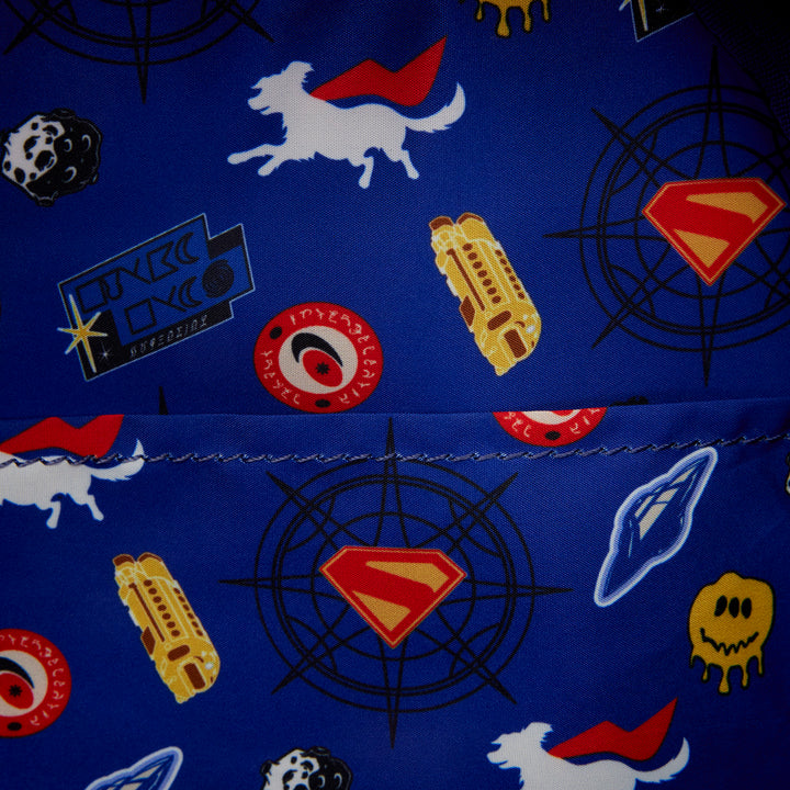 Close-up of a blue fabric with superhero-themed patterns including Superman logo, rocket, and alien.