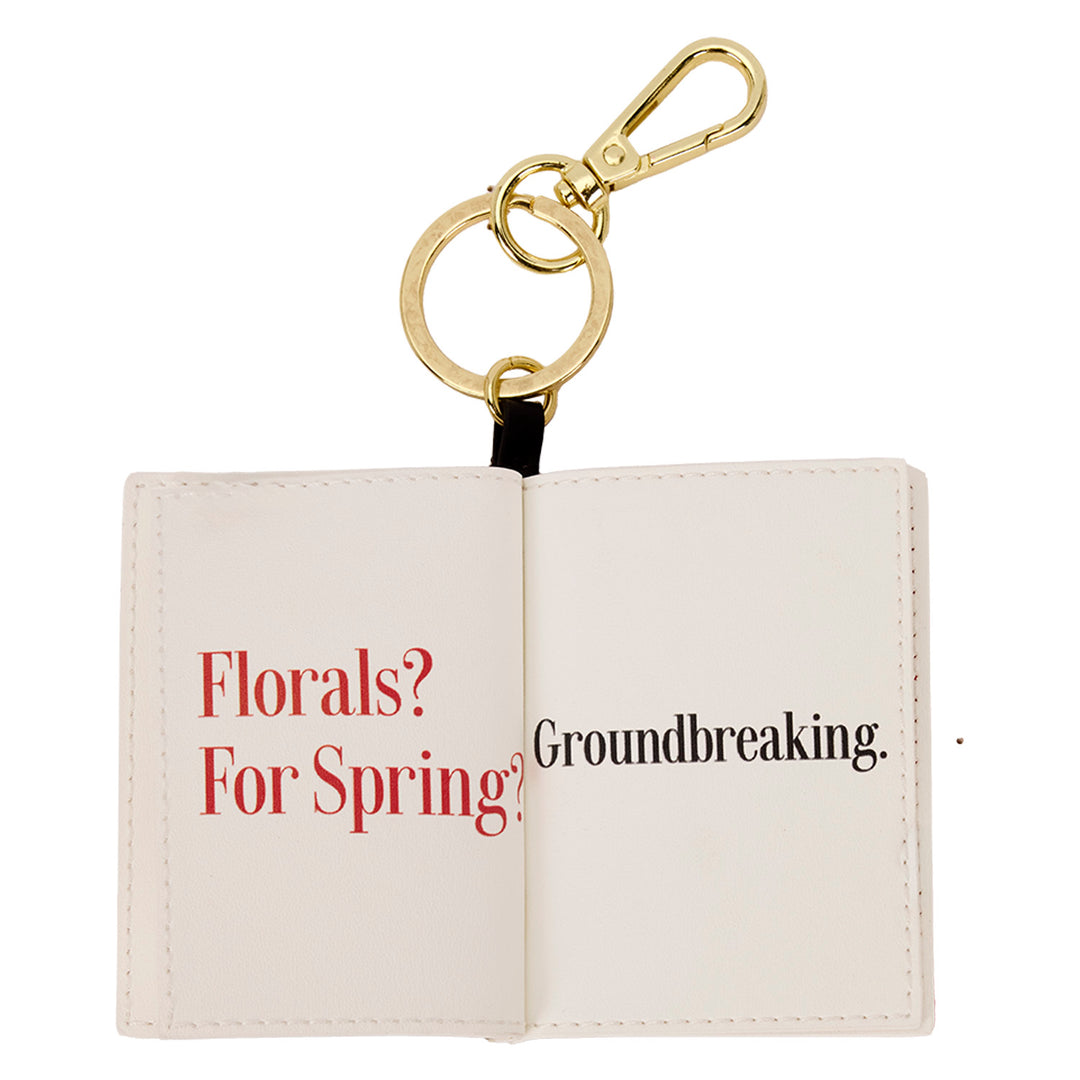 Keychain with open book design displaying text on a white background