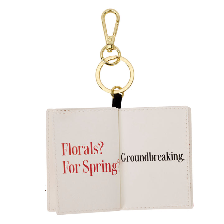 Keychain with open book design displaying text on a white background