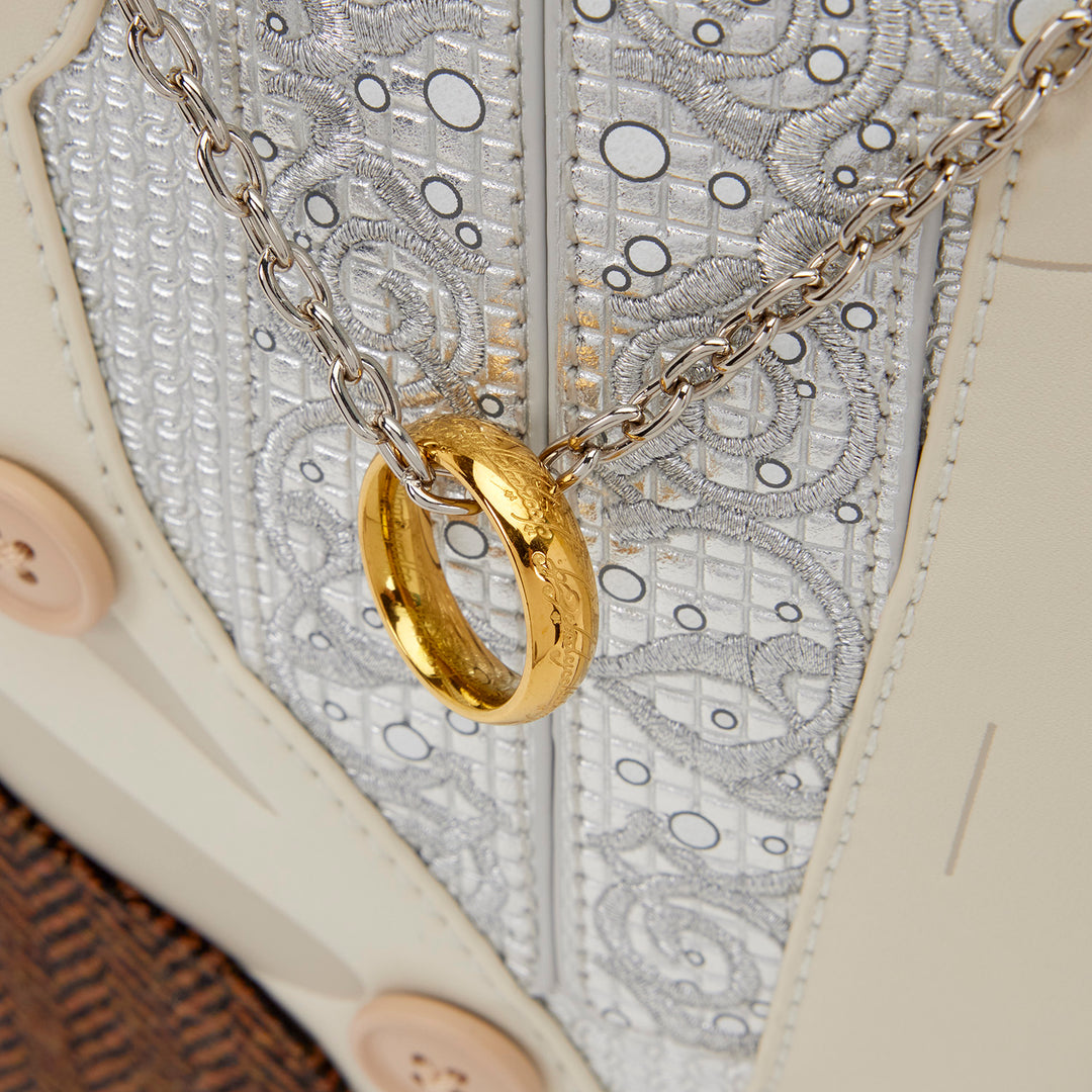 Gold ring pendant on a chain against a textured fabric background