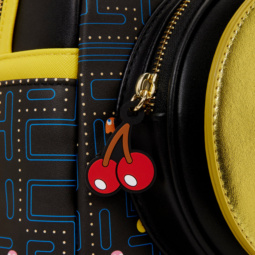 Close-up of a black bag with a cherry charm featuring a gold zipper.