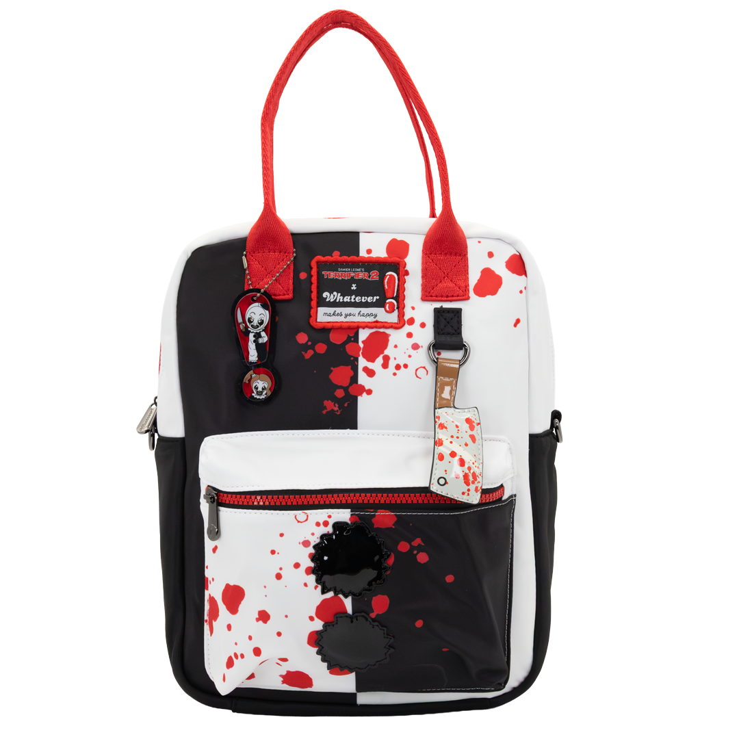 A white and black backpack with red handles and red blood-splatter print, featuring a front zip pocket with a black flower applique and a 'Whatever' brand patch.