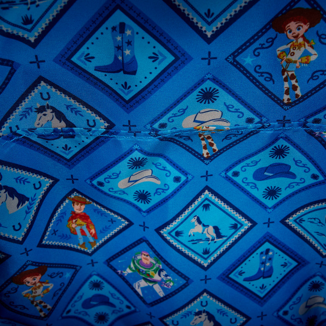Close-up of a blue fabric with cowboy-themed patterns featuring characters from Toy Story.