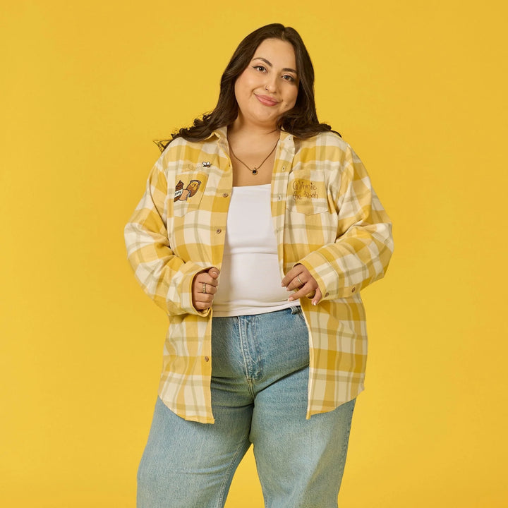 Woman wearing a yellow plaid shirt and blue jeans against a yellow background