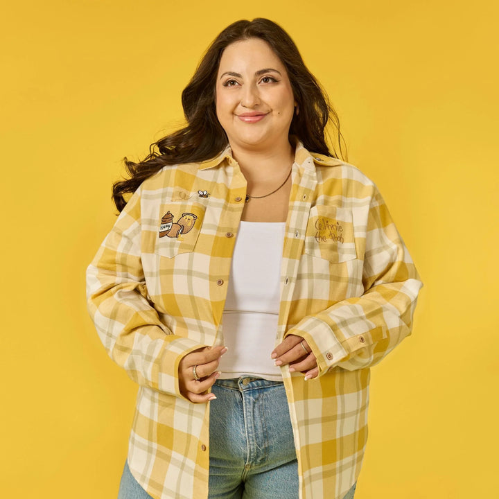 Woman wearing a yellow and white plaid shirt with patches on a yellow background