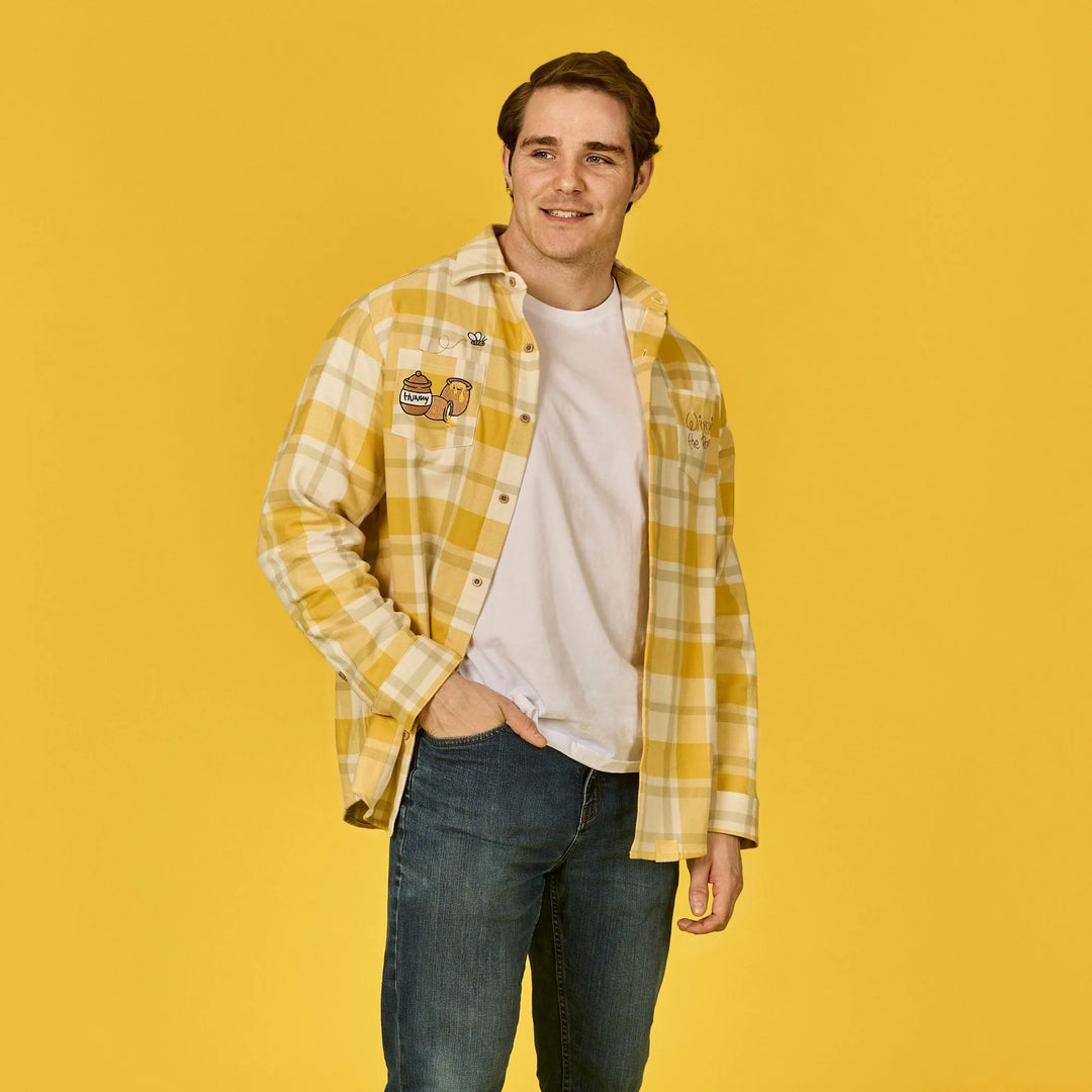 Man wearing a yellow plaid shirt over a white t-shirt on a yellow background