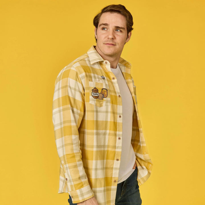 Man wearing a yellow plaid shirt with a logo on a yellow background