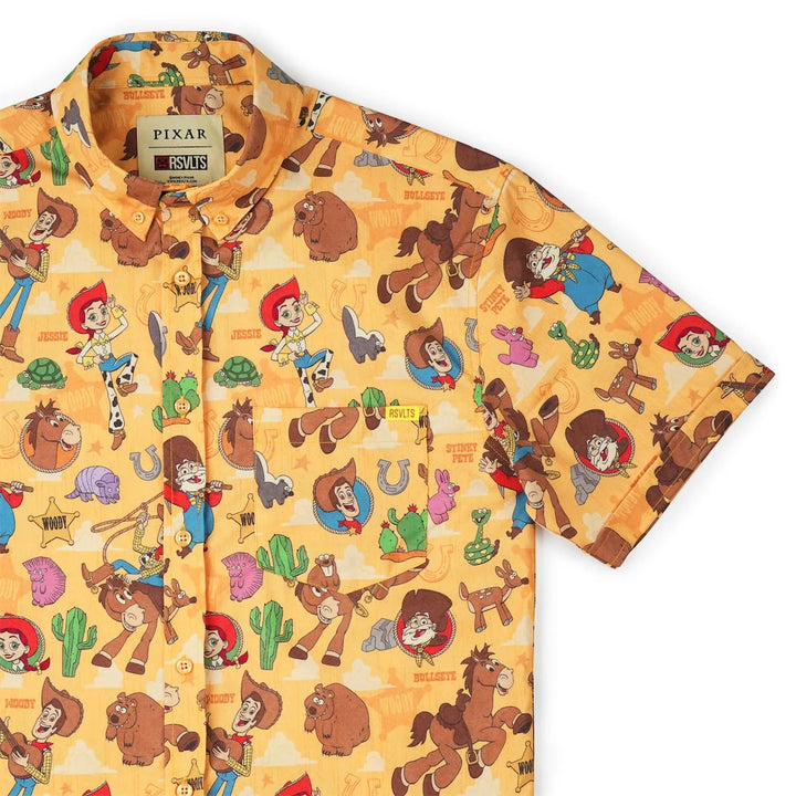 A short-sleeve button-up shirt featuring an all-over cartoon print from Pixar's Toy Story, displayed on a clean white background.